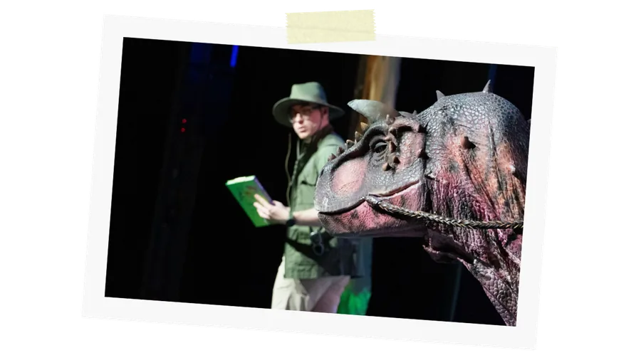 A ranger reads a field guide next to a dinosaur